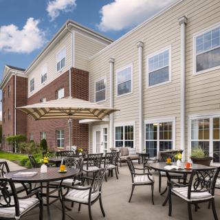 A cozy outdoor patio with tables, chairs, and umbrellas set against a modern residential building.