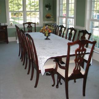 A dining room with a long table and chairs set up next to large windows.