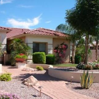 A beautifully landscaped desert garden with succulents and cacti in front of a house.