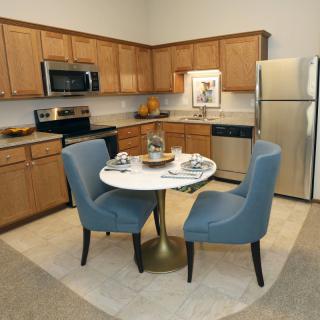 A modern kitchen with wood cabinets and a cozy dining area featuring a round table and blue chairs.