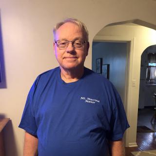 A man in a blue shirt poses for a photo indoors.