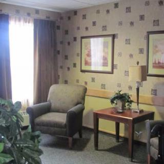 A cozy living room setting featuring comfortable chairs, a small table with a plant, and decorative wall art.