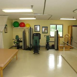 A well-equipped physical therapy room with exercise machines and therapy tables.