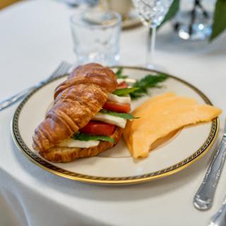A delicious breakfast featuring a croissant filled with fresh vegetables and a side of cheese.