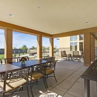 A spacious patio with a dining table and chairs, surrounded by open views on a sunny day.