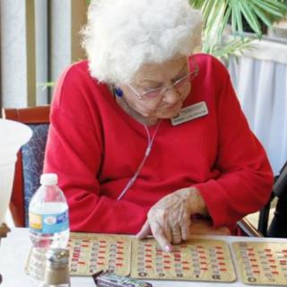 An elderly person focused on playing bingo at a table.