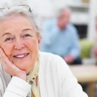 An elderly woman smiling indoors.