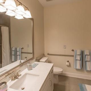 A neat and well-lit bathroom with a large mirror and neatly arranged towels.