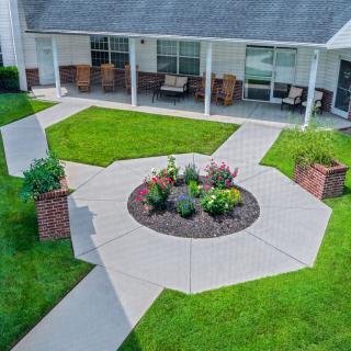 A well-maintained garden with a central flower bed surrounded by pathways and outdoor seating.
