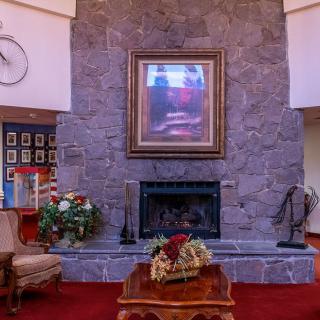 A cozy living room with a stone fireplace and artwork above, surrounded by elegant furniture and decor.