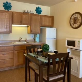 A cozy kitchen and dining area with wooden cabinets, a microwave, and a small dining table set.