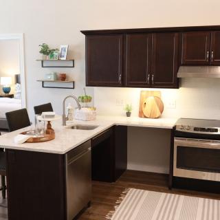 A modern kitchen with dark cabinets, stainless steel appliances, and a cozy dining area.
