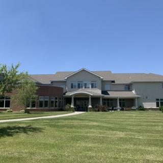 A large suburban house with a spacious lawn under a clear blue sky.