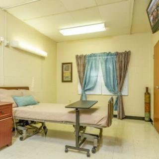 A clean and organized hospital room with a bed, TV, and curtains.
