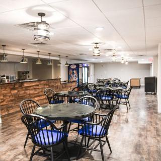 A modern restaurant interior featuring a spacious dining area with tables, chairs, and a wooden bar counter.