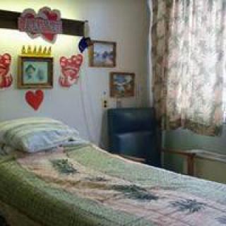 A decorated hospital room with a bed and a chair by the window.