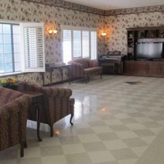A spacious living room with patterned wallpaper, featuring sofas and a television.