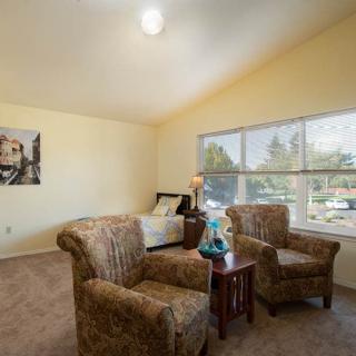 A cozy living room with two armchairs, a small table, and a large window allowing natural light in.