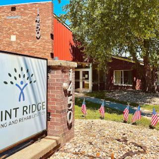 The entrance of a community center with flags and greenery, showcasing the name 'Pinnacle Ridge'.