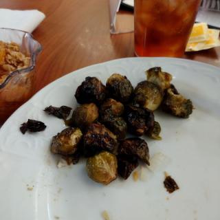 A plate of roasted Brussels sprouts served with a drink.