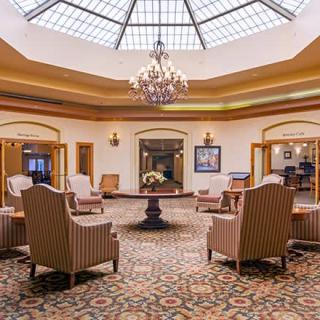 A luxurious lobby with comfortable seating, a central table, and a stunning chandelier under a dome-shaped ceiling.