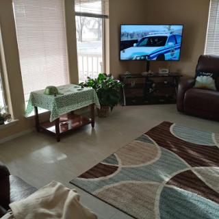 A cozy living room featuring a television, comfortable seating, and decorative plants.