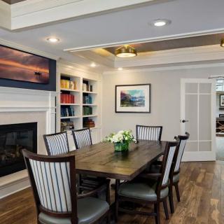 A modern dining room featuring a fireplace, bookshelves, and a hardwood floor.