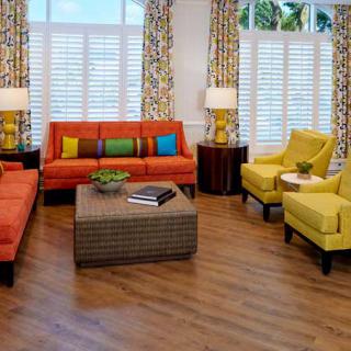 A vibrant living room with colorful sofas, armchairs, and patterned curtains.