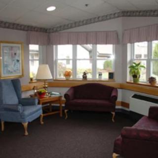 A cozy waiting room with comfortable chairs, side tables, and large windows letting in natural light.
