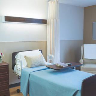 A clean and organized hospital room with a single bed and chair.