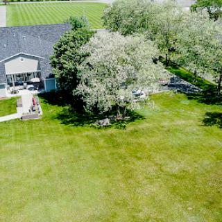 Aerial view of a serene house surrounded by lush greenery and a spacious lawn.