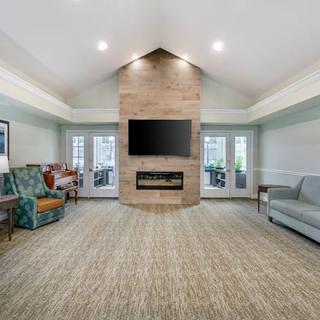 A modern living room featuring a central fireplace with a mounted television, surrounded by comfortable seating and a vaulted ceiling.