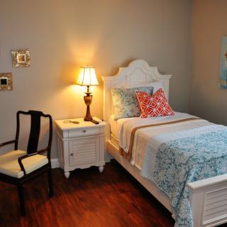 A cozy bedroom with a neatly made bed, an elegant nightstand, and a warm lamp illuminating the space.