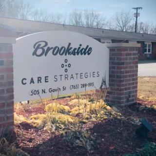 Sign for Brookside Care Strategies at the entrance of a facility, surrounded by landscaping.