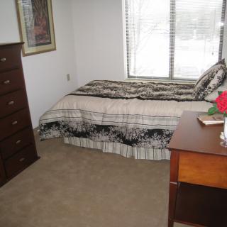 A tidy bedroom with a bed, dresser, and window.