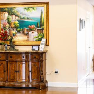 A cozy living space featuring a wooden cabinet adorned with a vibrant painting and decorative flowers.