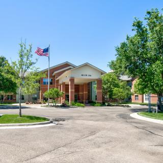 A hotel entrance with a driveway, surrounded by trees and an American flag flying outside.