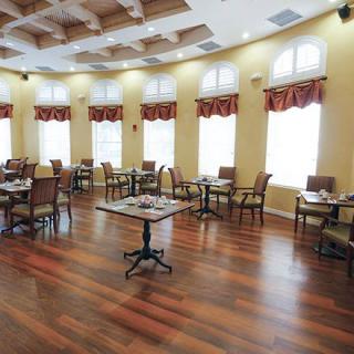 A spacious and elegantly decorated dining room with wooden floors and multiple tables and chairs.