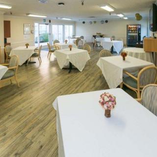 A neatly arranged dining area with tables covered in white tablecloths and small flower vases.
