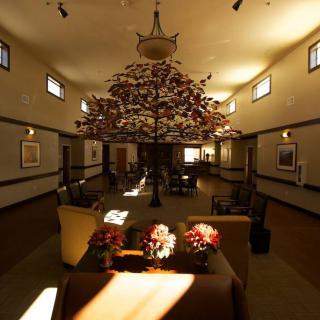 A beautifully lit lobby with a central tree sculpture and comfortable seating area.