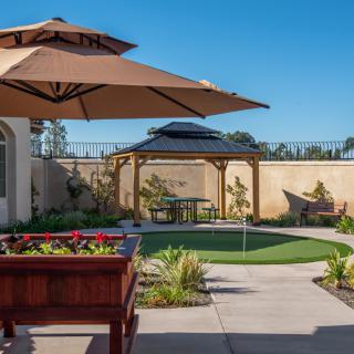 A beautifully landscaped backyard with a patio, outdoor furniture, and a gazebo.