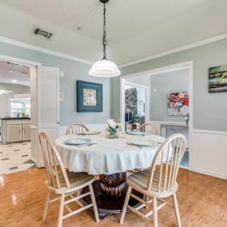 A cozy dining area with a round table and wooden chairs, highlighted by a central light fixture.
