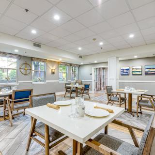 A modern restaurant interior with neatly arranged tables and chairs under bright lighting.