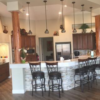A modern kitchen with an open concept featuring a stone counter bar area and elegant pendant lighting.