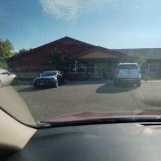 A view of a parking lot with several cars parked in front of a building on a sunny day.