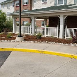 A well-maintained entrance to a residential building with landscaped flower beds and a clearly marked pathway.