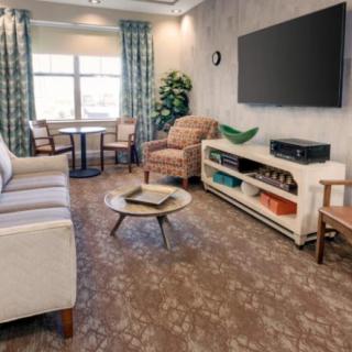 A cozy living room with a sofa, armchairs, and a large television on the wall.