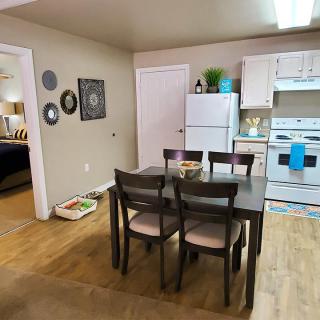 A modern kitchen and dining area with a table set for four, featuring a white refrigerator and stove.