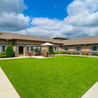 A spacious courtyard with a well-maintained lawn surrounded by a modern building under a partly cloudy sky.