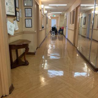 A polished hallway with a wheelchair at the end and framed items on the walls.